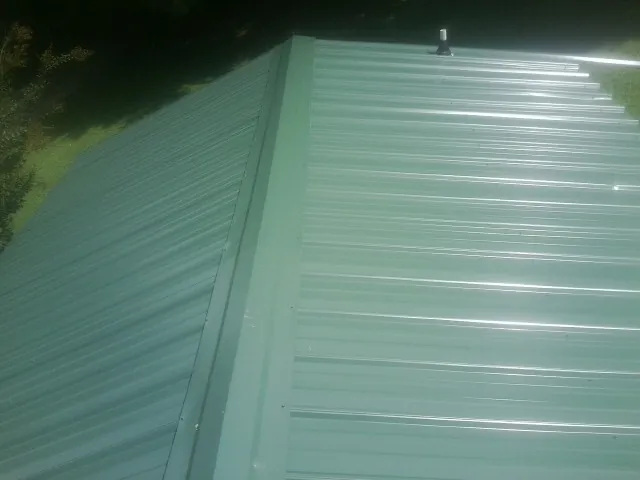New green metal panels meeting at the ridge of a roof — Flat Roof Repair work by our crew in Granger