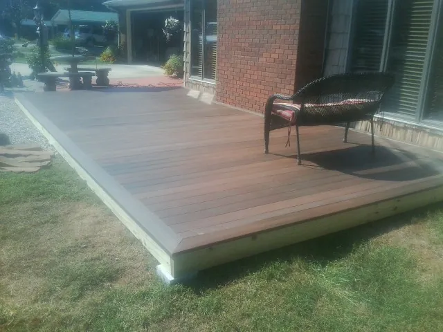 New wood deck and wicker chair beside a brick house in Granger